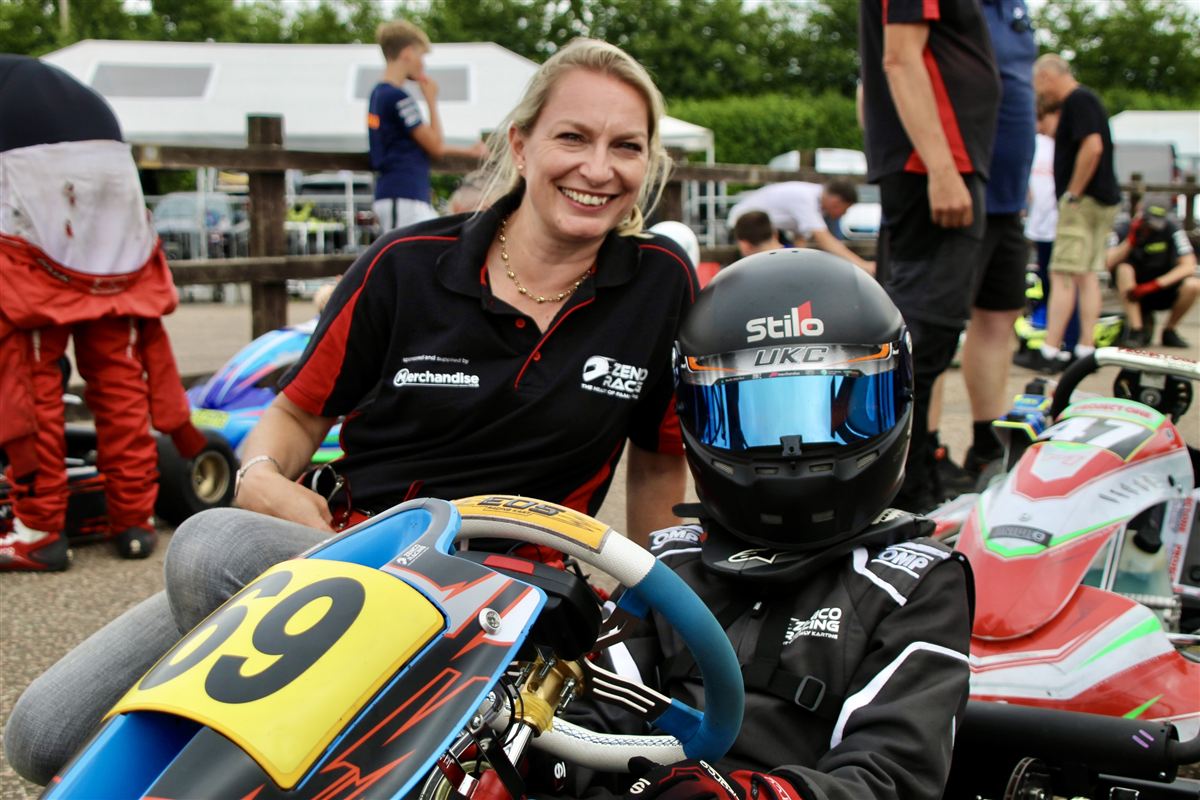 Emma smiling beside Zak in his kart, number 69, in the paddock