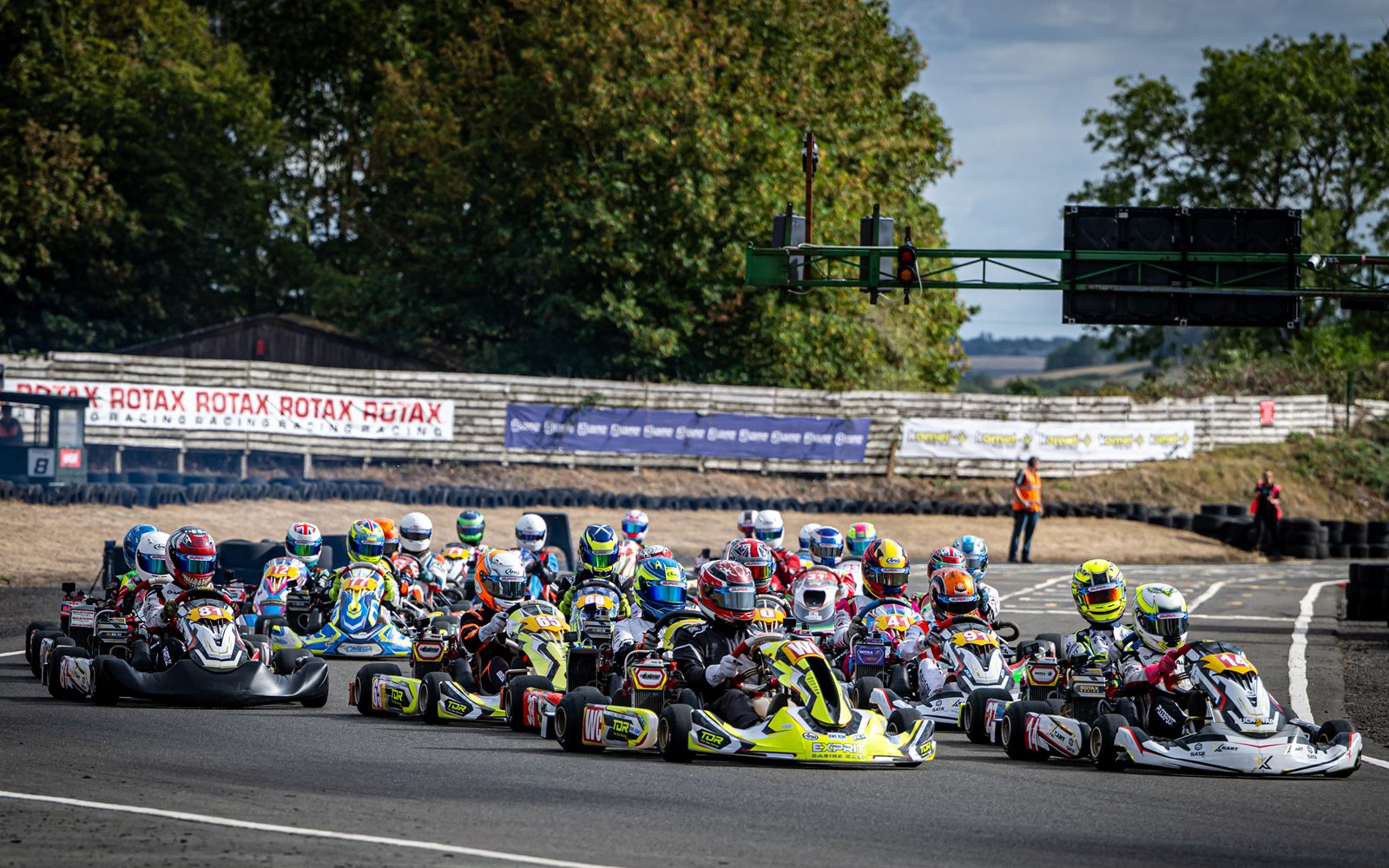 A full grid of Junior Rotax karts leaving the start at a Super One round at Shenington