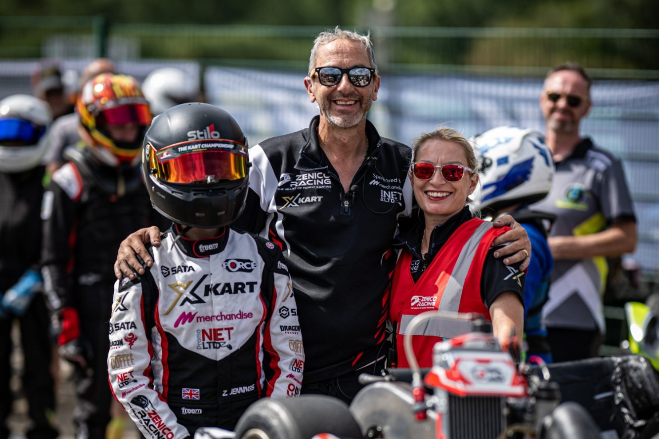 Zak, Andy and Emma of Zenico Racing smiling together in the paddock with kart number 69